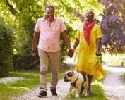 man and woman walking their dog at the park