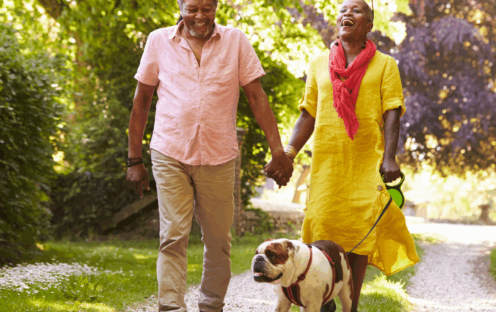 man and woman walking their dog at the park