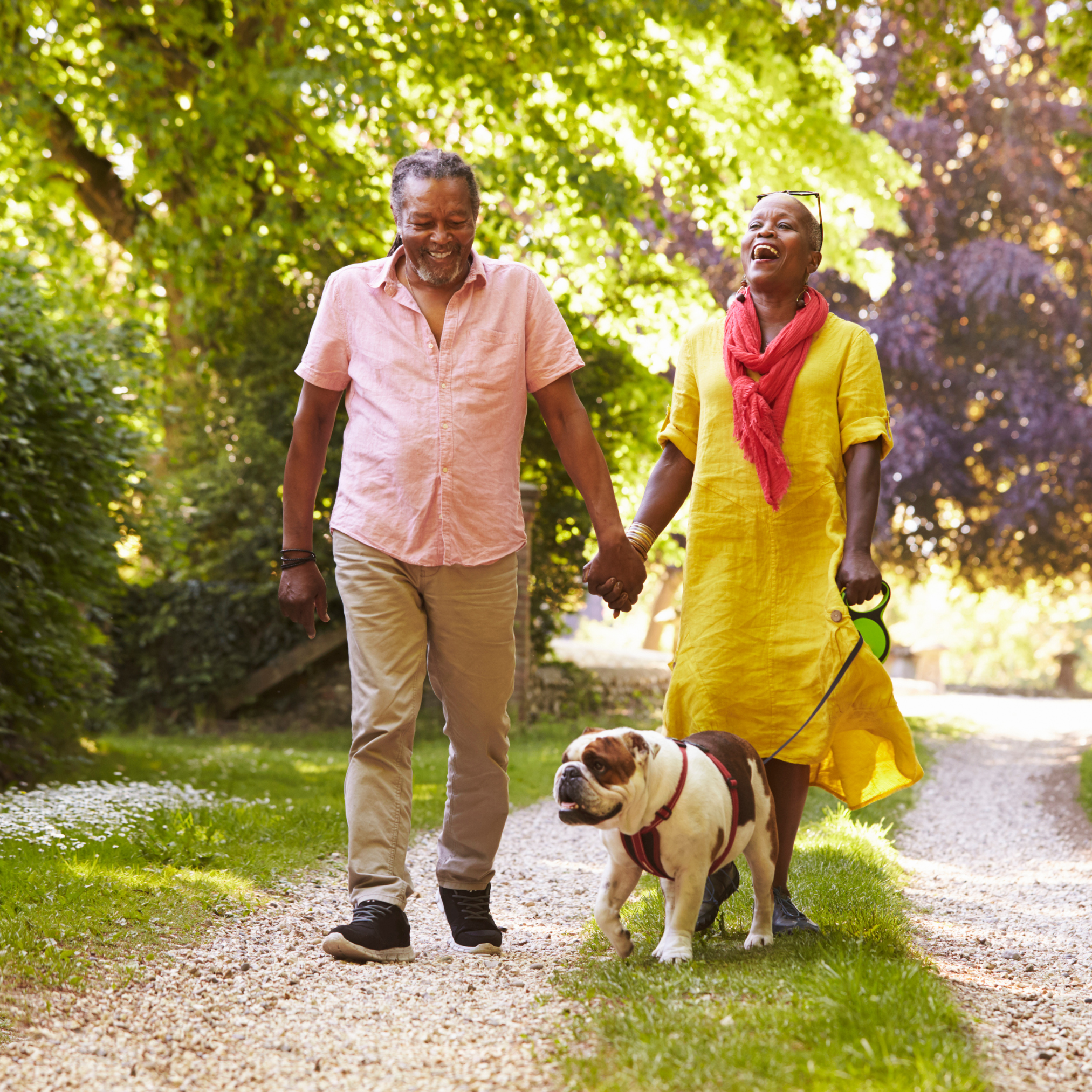 man and woman walking their dog at the park